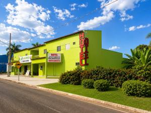 a yellow and green building with a neon sign on it at Hotel Natureza in Anhanduí
