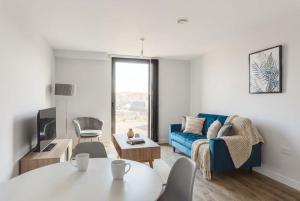 a living room with a blue couch and a table at Central Birmingham 2 BED Modern Spacious Apartment in Birmingham