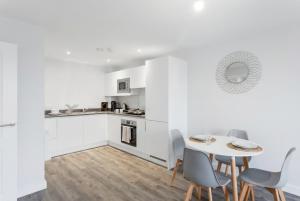 a white kitchen with a table and chairs at Central Birmingham 2 BED Modern Spacious Apartment in Birmingham +15 photos