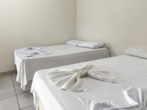two beds with white sheets and a bow on them at Hotel Natureza in Anhanduí