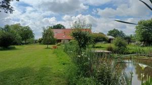 a house in a field next to a body of water at gite art et nature in Thorigny