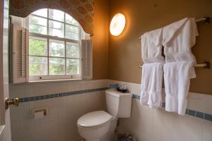 a bathroom with a toilet and a window and towels at Beaumont Inn in Harrodsburg