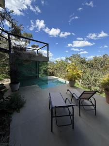 a patio with two chairs and a table and a pool at Casa Capim Limão in Cavalcante