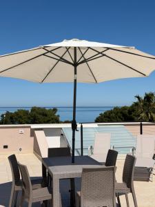 a table and chairs with an umbrella on a balcony at Luxekey ETTORE HOUSE in Scopello
