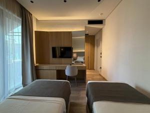 a hotel room with two beds and a television at Riviera Boutique Hotel by Pomo d'oro in Vlorë