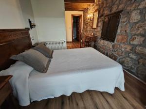 a bedroom with a large bed in a stone wall at Posada La Colodra in Los Tojos