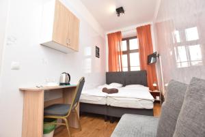 a small room with a bed and a desk with a chair at City Central Hostel - Pokoje prywatne in Wrocław