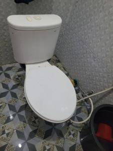 a white toilet in a bathroom with a hose at The Sinta Bali in Munduk