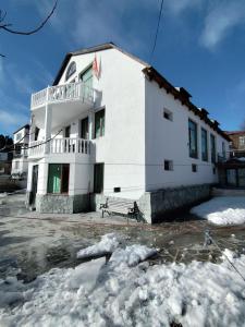 a white building with a bench in the snow at Hotel Meridiane in Bakuriani