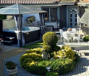 a garden with an umbrella and a hot tub at Kristály Pihenőház in Szekszárd
