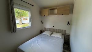 a small bedroom with a bed and a window at Camping le Martin Pêcheur in Magné