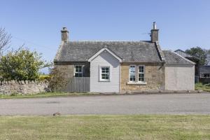 an old stone house with a dog in front of it at Fordel Cottage in Dalkeith