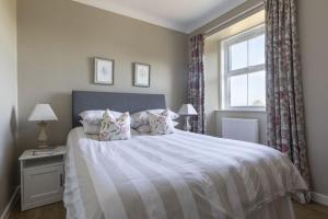 a bedroom with a large bed with a window at Fordel Cottage in Dalkeith