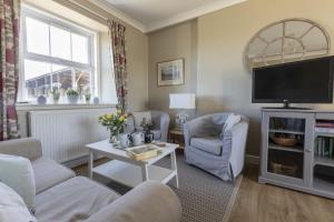 a living room with a couch and chairs and a tv at Fordel Cottage in Dalkeith
