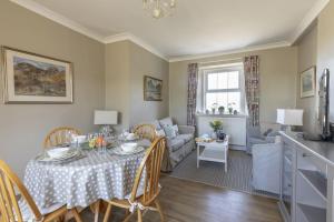 a dining room and living room with a table and a couch at Fordel Cottage in Dalkeith