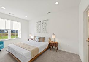 a white bedroom with a large bed and two windows at Modern Townhouse with Pool Gym & Tennis Near Beach in Ocean View