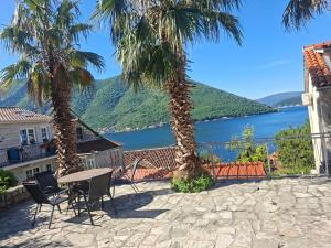 a patio with two palm trees and a table and chairs at Apartman Perast in Perast