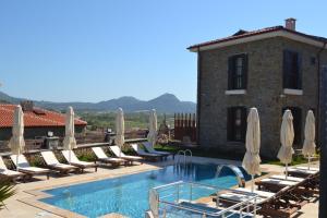a pool with chairs and umbrellas next to a building at Mathilda Gökçeada in Gokceada Town