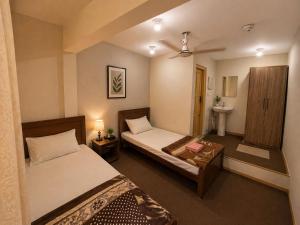 a bedroom with two beds and a sink at Highlander inn Skardu in Skardu