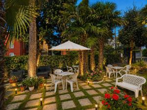 a patio with chairs and an umbrella and flowers at Hotel Villa Pina in Senigallia +44 photos