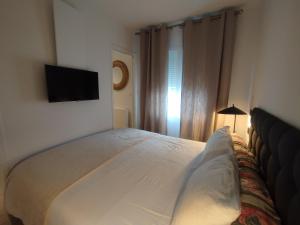 a bedroom with a white bed and a television at Studio à la VILLA VOLTAIRE in Clamart
