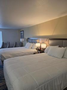 two beds in a hotel room with two lamps at Omak Inn in Omak +14 photos