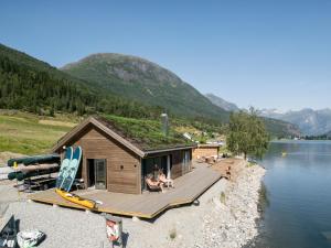 a cabin with a grass roof on a lake at Stryn Golden Resort - Panorama II in Stryn
