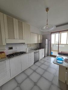 a kitchen with white cabinets and a white tile floor at Appartamento Polidea in Reggio di Calabria