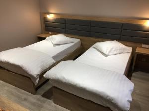 two beds in a room with white sheets and pillows at Auberge La Veranda in Luxembourg