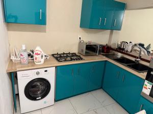 a kitchen with blue cabinets and a washing machine at Maeva Tana in Tsingoni