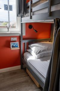 a bunk bed in a room with an orange wall at Railway Sleeper Hostel in Castlerock