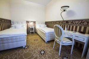 a bedroom with two beds and a desk and a chair at Golden Royal Boutique Hotel & Spa in Košice