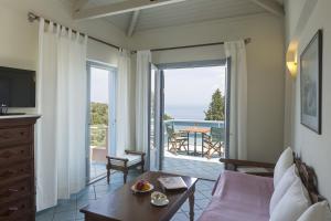 a living room with a couch and a television and a balcony at MIRA Resort Maizonettes in Lefkada