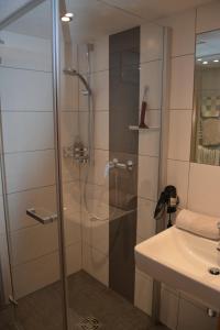 a shower with a glass door next to a sink at Gästehaus Huber in Leogang