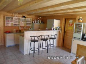a kitchen with three bar stools at a counter at Jausenstation Neuschwand in Hittisau