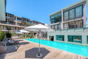 a swimming pool with an umbrella and a building at Skyline Living, Table Mountain Views in Cape Town