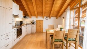 a kitchen with a wooden ceiling and a table and chairs at AlpStern Ferienwohnungen Oberstdorf in Oberstdorf