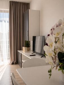 a white living room with a tv and a table at Nolia Apartments in Bucharest
