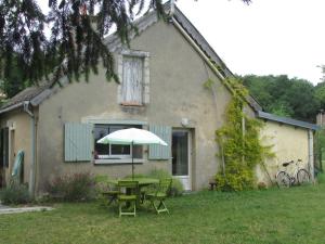 a table with an umbrella in front of a house at Gite la petite pataudiere in Le Guédéniau