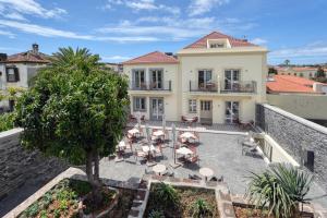 a house with a courtyard with chairs and a tree at Chapelaria Boutique Hotel in Funchal