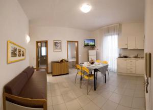 a living room and a kitchen with a table and yellow chairs at Residence Caterina in Cattolica