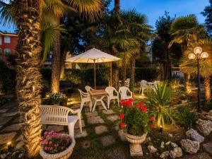 a patio with chairs and an umbrella and palm trees at Hotel Villa Pina in Senigallia