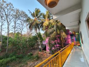 a balcony of a pink house with palm trees at The Long Stay Goa in Arambol