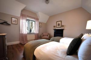 a bedroom with two beds and a chair and a fireplace at The Gatehouse in Peterborough