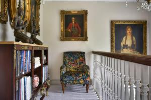 a room with two portraits and a chair and a book shelf at Morland Manor in Peterborough