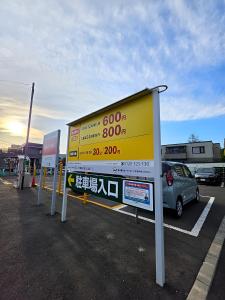 a yellow billboard in a parking lot with a car at Snow Nest Lodge in Sapporo
