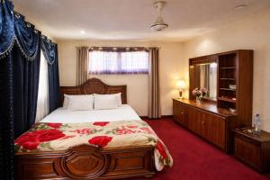 a bedroom with a bed and a dresser and a window at Highlander inn Skardu in Skardu
