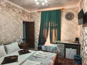 a bedroom with two beds and a desk and a window at Hotel Nazira & Azizbek in Bukhara