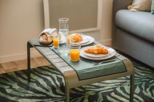 a table with two plates of food and glasses of orange juice at Studio L'Émeraude - F1 lumineux, hypercentre - CAEN in Caen +6 photos