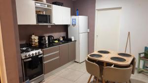 a small kitchen with a table and a refrigerator at Duplex Jardines del Rey in Neuquén